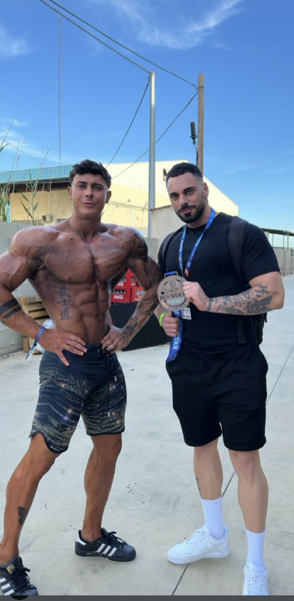 Riccardo Matterazzo mostra la medaglia della gara accanto al suo atleta di Men's Physique